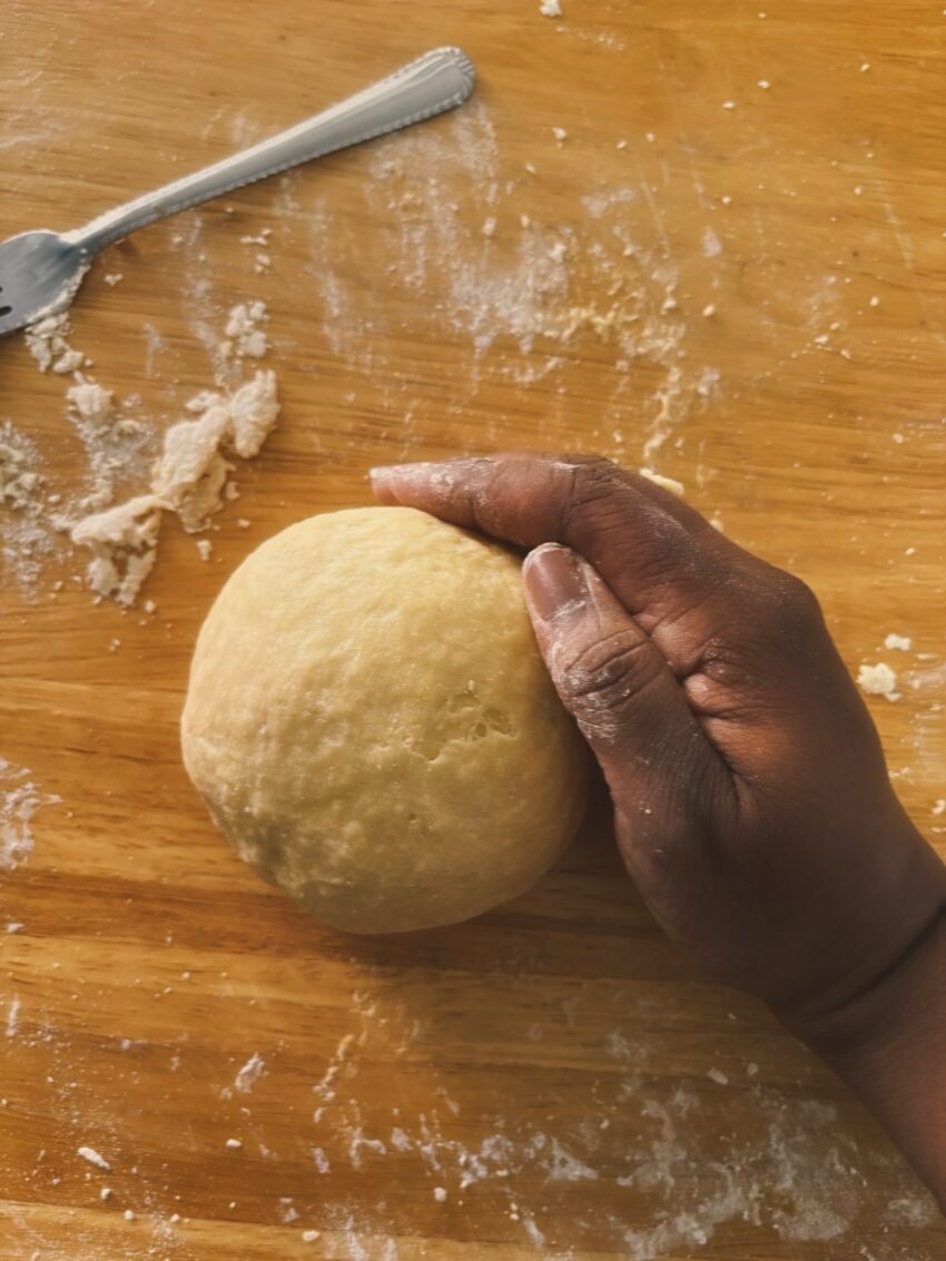 A close-up of a hand holding freshly rolled pasta dough as it is shaped during the process of making homemade pasta.