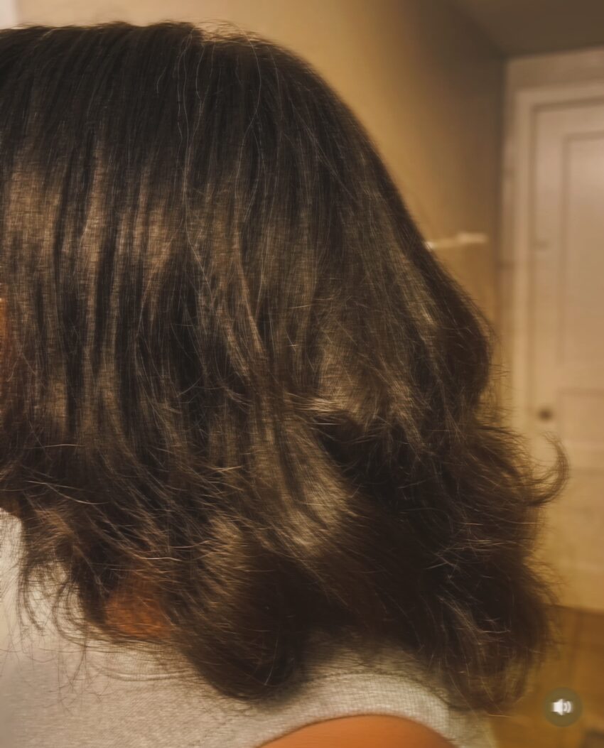 A partial back view of thick, relaxed hair showing soft waves and visible volume.