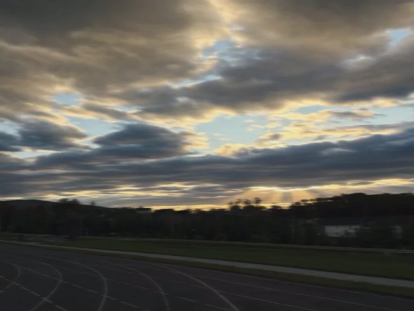 Running track at dusk with clouds and fading light over a quiet neighborhood.