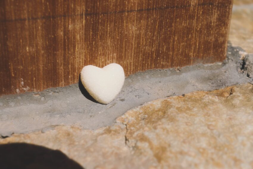 A small white heart-shaped object propped against a post on a sidewalk along a town’s Main Street.