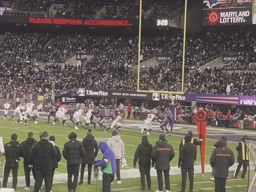 View from the stands at an NFL game on Thanksgiving night with players lined up on the field.